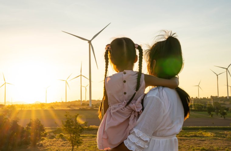 kvinne holder ungen sin og ser utover vindmøller