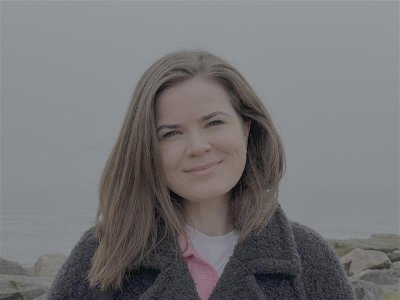 Kvinne smiler inn i kamera utendørs