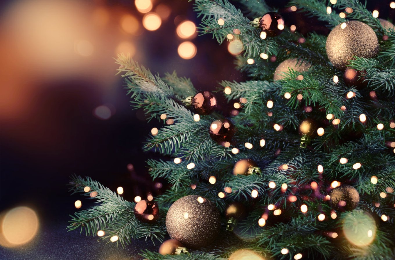 Juletre pyntet med lys og kuler, med en stemningsfull bakgrunn av bokeh-lys.