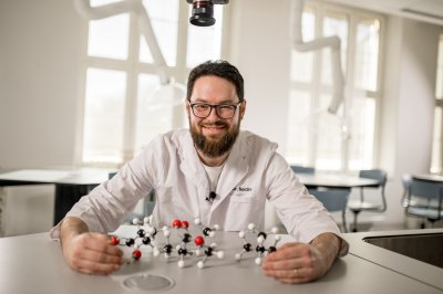 Mann i labfrakk holder molekylmodell i et moderne laboratorium.