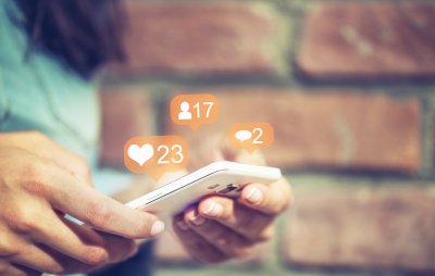 Person bruker smarttelefon med sosiale medier-ikoner for likes, kommentarer og følgere.