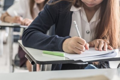 Student som skriver på en eksamen ved en pult i et klasserom.