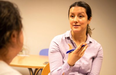Lærer forklarer noe til en elev i et klasserom.