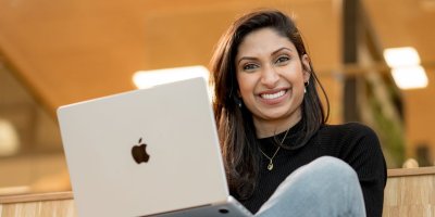 Bilde av nettstudent som jobber på PC og smiler til kameraet