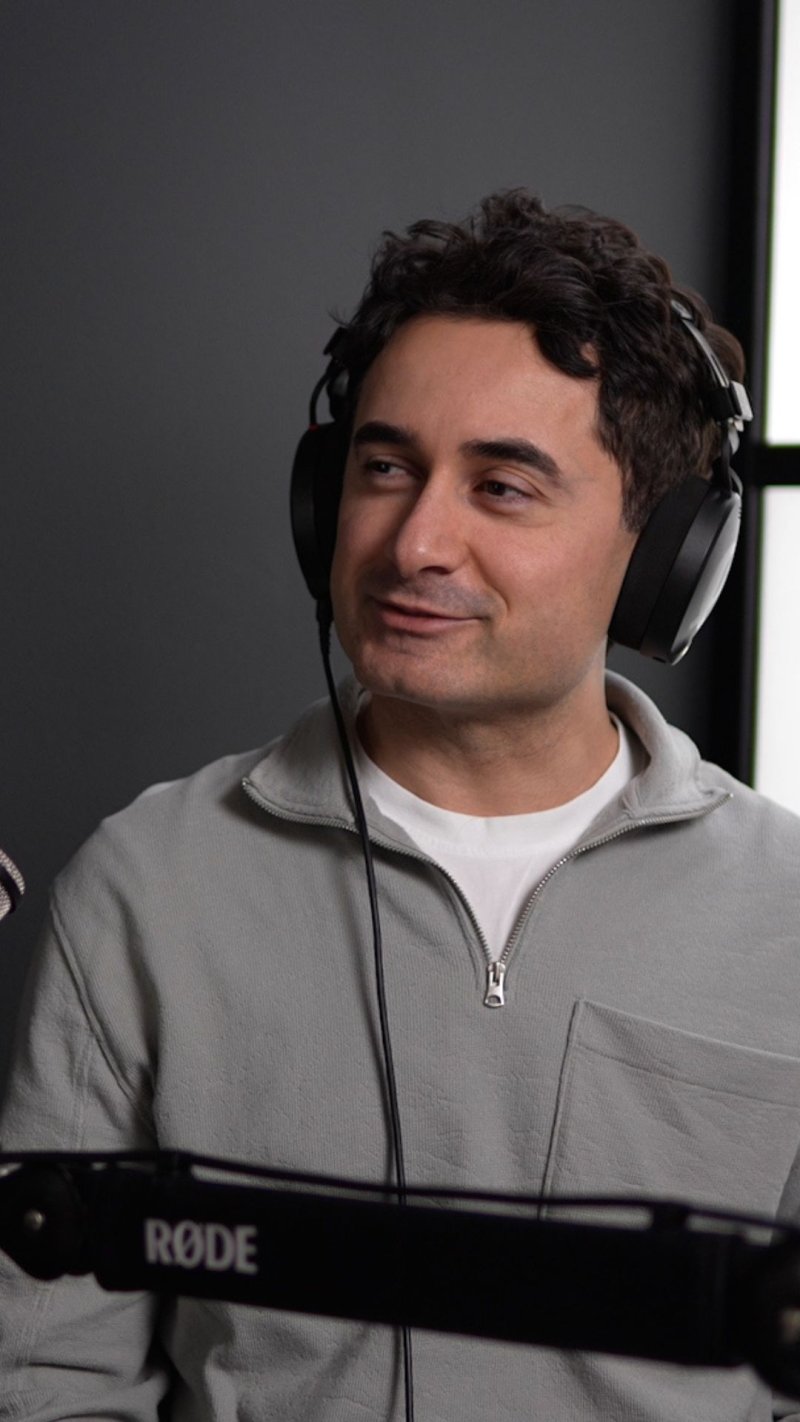 Mann med hodetelefoner smiler under en podcast-innspilling.
