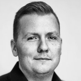 Portrett av en mann med kort hår og skjorte, ser rett inn i kameraet.