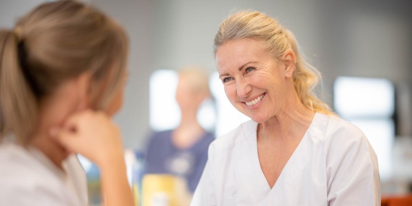 Smilende blond kvinne øver seg på blodprøvetaking på medstudent