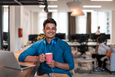 Smilende mannlig student i åpent kontorlandskap 