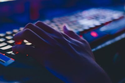 Hånd på et opplyst tastatur i et mørkt rom.