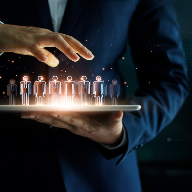 Person holder nettbrett med holografiske figurer som representerer digitalt lederskap og selvledelse.