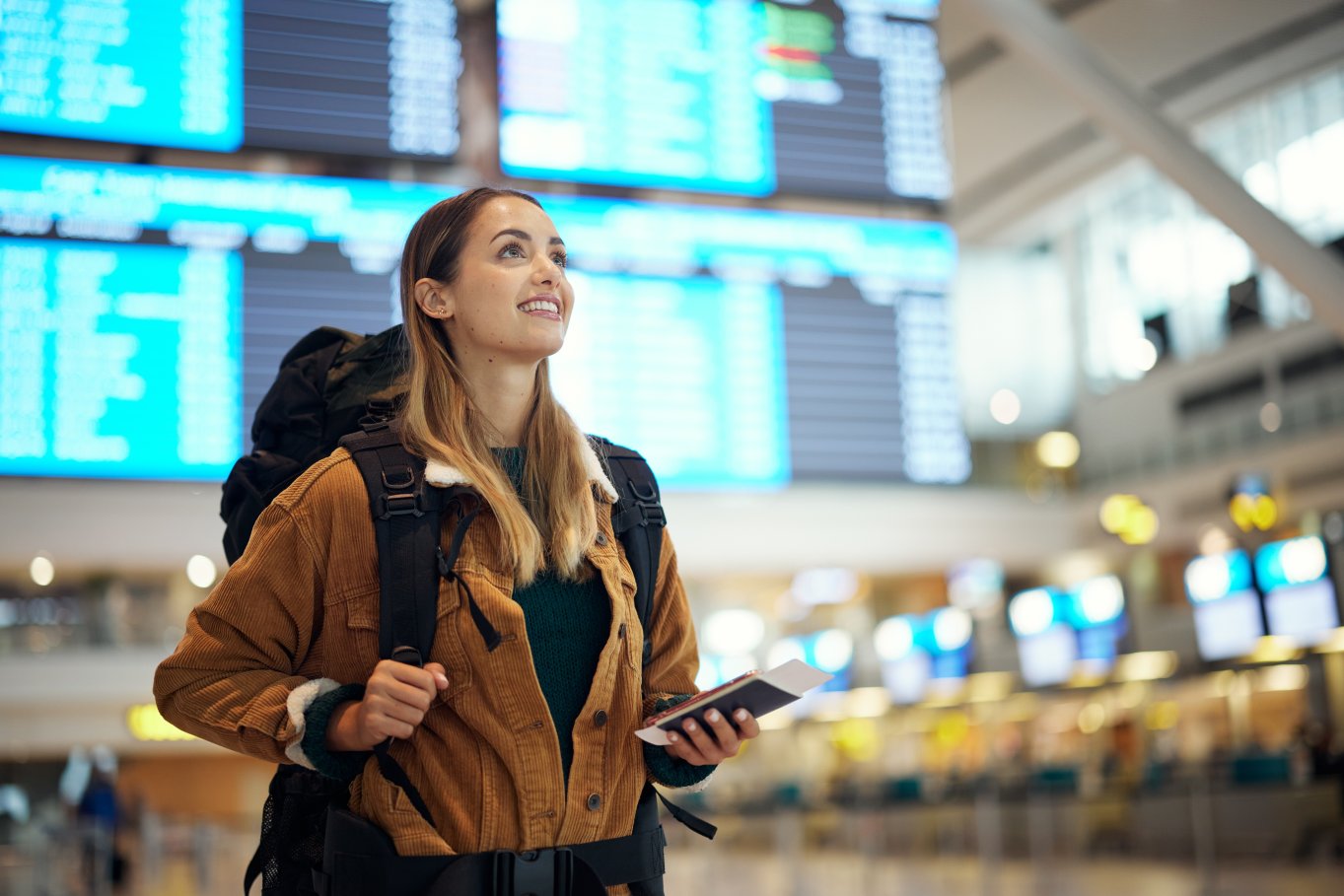 smilende kvinne på flyplass m rygsekk