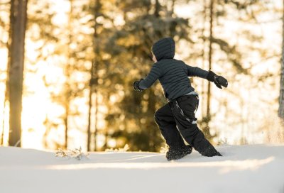 Et barn løper i snøen i skogen 