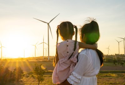 kvinne holder ungen sin og ser utover vindmøller