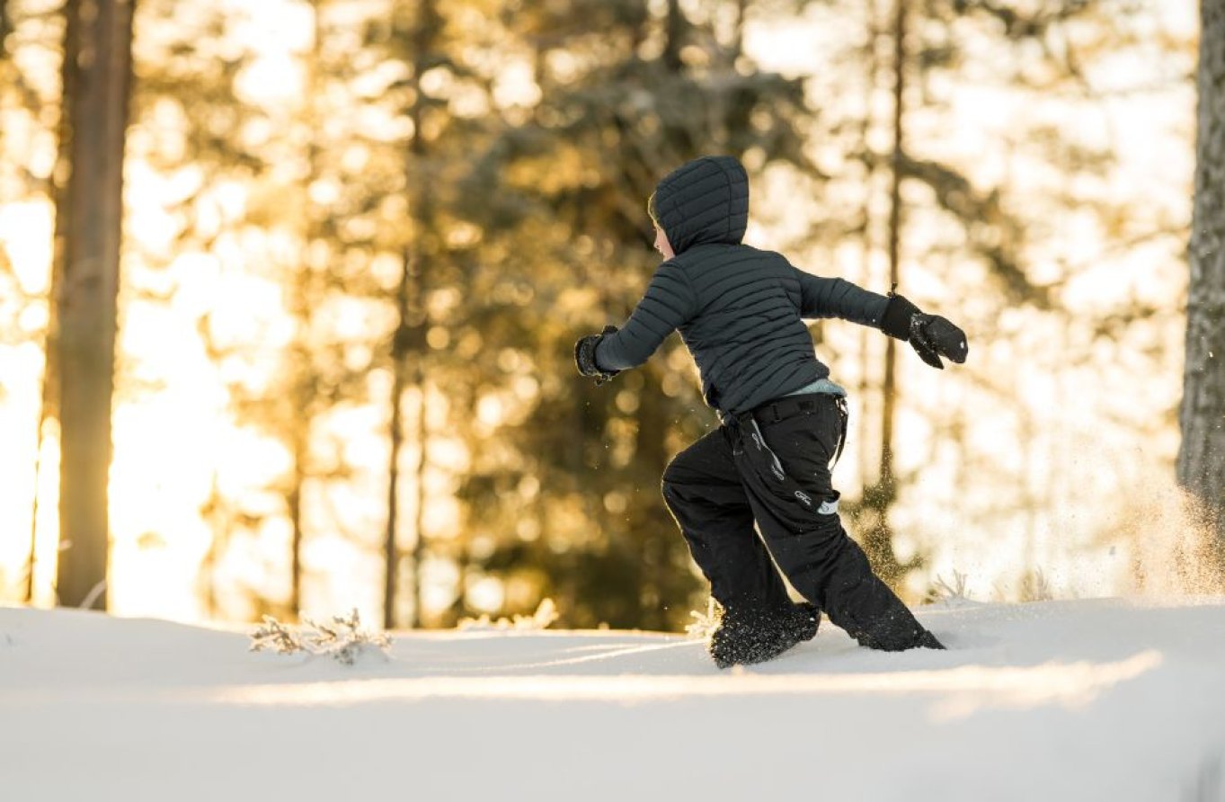 Et barn løper i snøen i skogen 