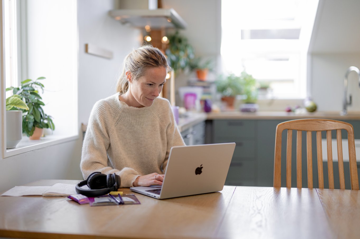 Student jobber på en laptop ved et kjøkkenbord i et lyst hjemmemiljø