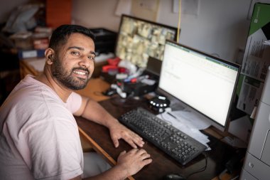 Mann foran pc smiler til kamera