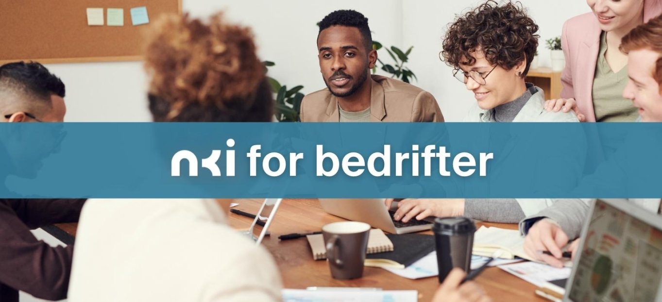 Fem personer diskuterer rundt et bord med NKI for bedrifter-banner i forgrunnen.