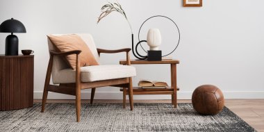 Moderne stue med lenestol, bord, lampe og dekorasjoner i nøytrale farger.