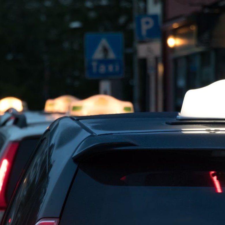 Taxier står parkert på rad langs en gate om kvelden.