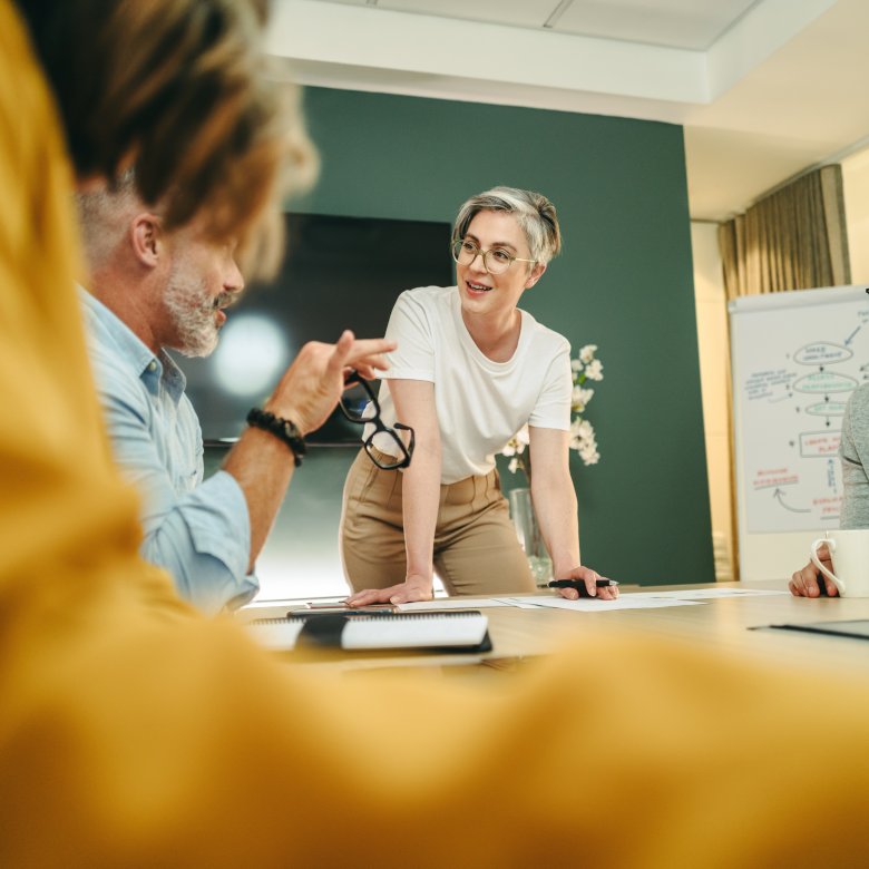 Personer diskuterer strategisk ledelse og innovasjon i et møterom.