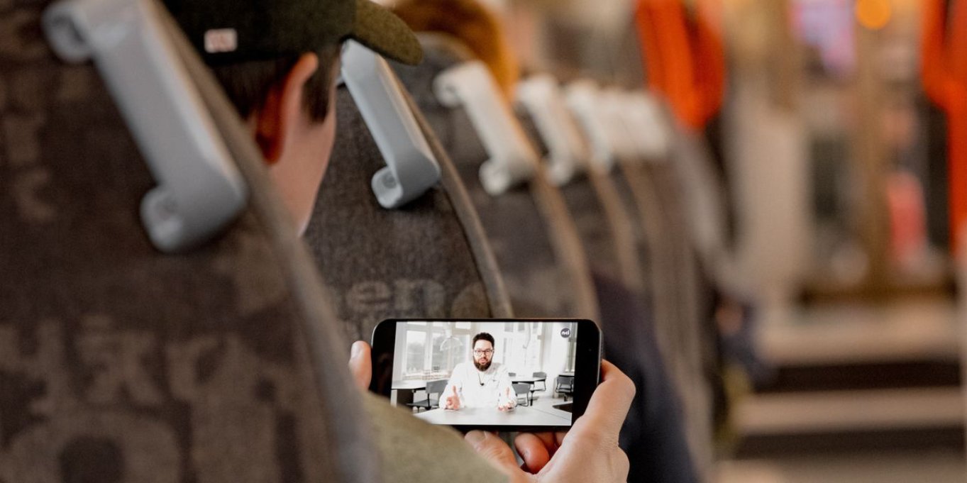 Person ser på en video på mobilen mens de sitter på et tog.
