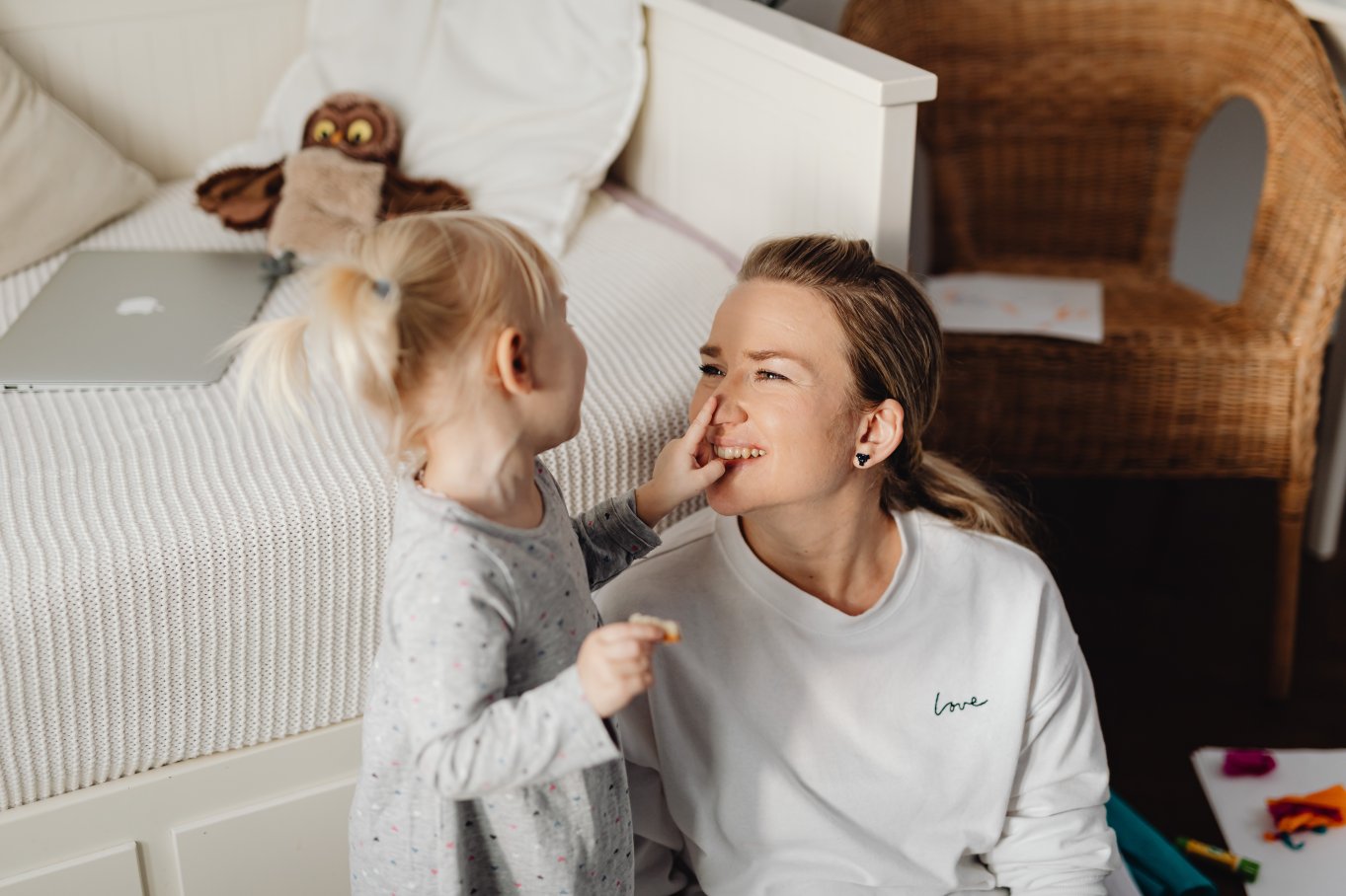 Barn og voksen smiler og leker sammen i et koselig rom.
