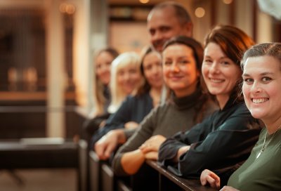 En gruppe smilende mennesker står på rekke innendørs.