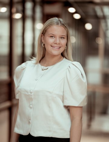 Kvinne i hvit bluse smiler i kamera