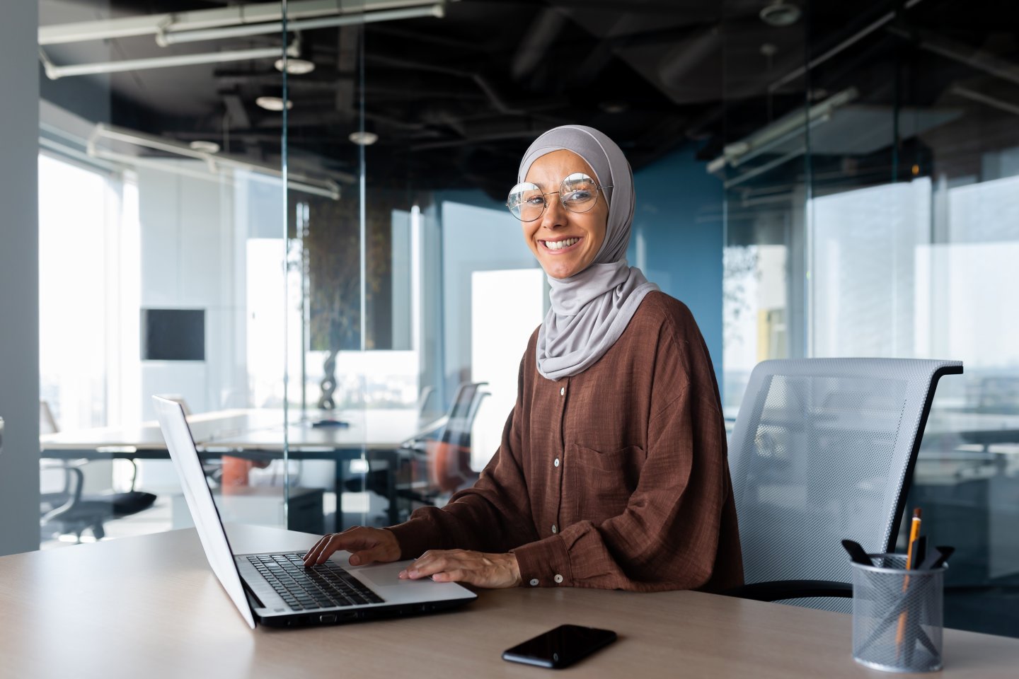 Kvinne sitter ved pulten og jobber på PC