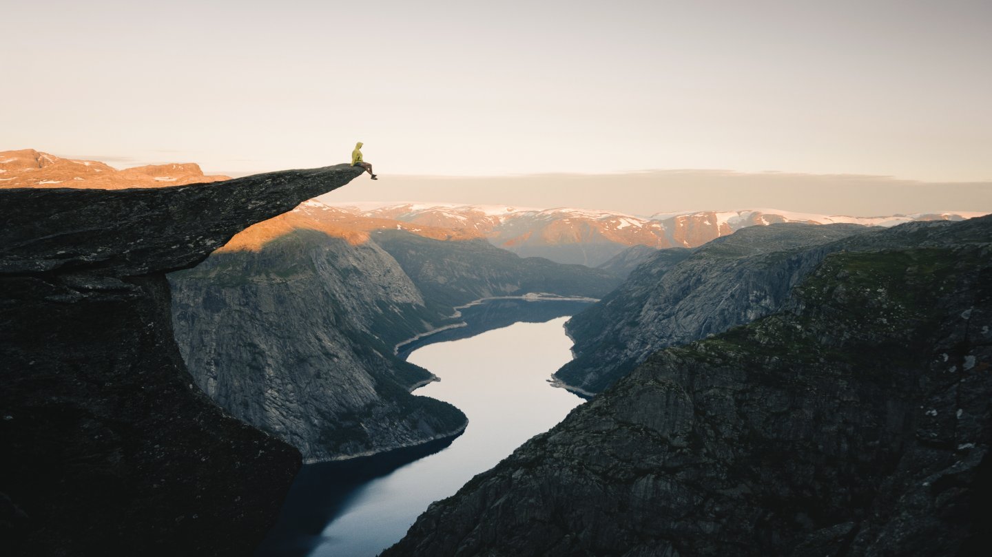 Person sitter på trolltunga og ser utover utsikten