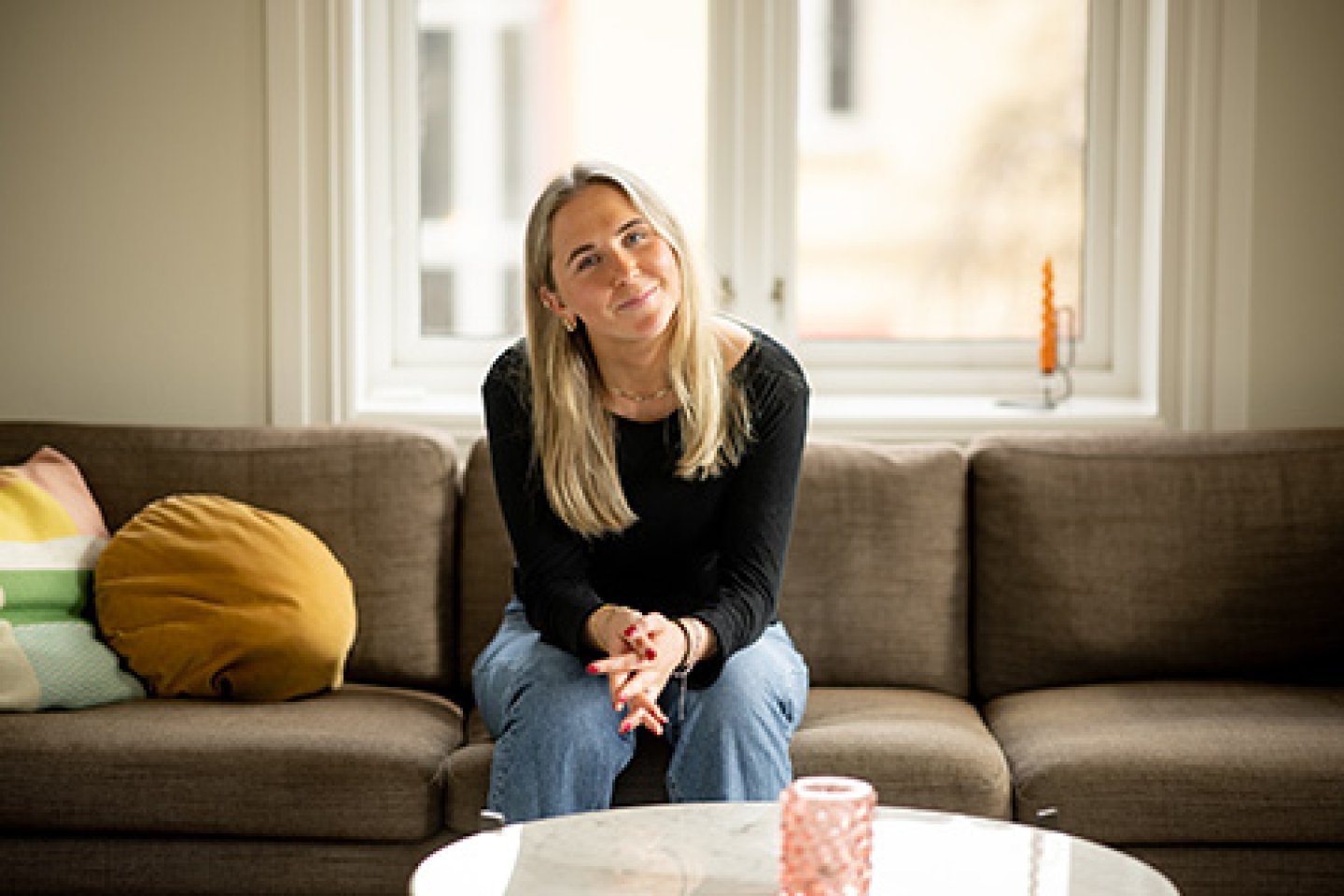 Jente sitter i sofaen og smiler