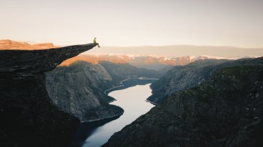 Person sitter på trolltunga og ser utover utsikten