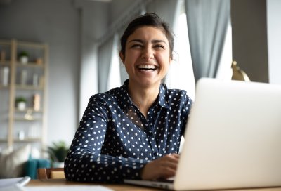 Smilende kvinne sitter ved PC