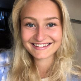 Smilende kvinne med blondt hår ser inn i kameraet.