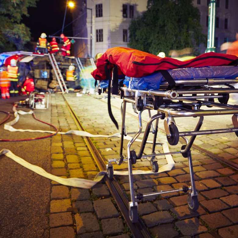 Ambulansepersonell jobber på ulykkessted om natten med båre i forgrunnen.