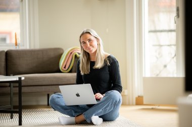 Jente sitter på gulvet med laptop og studerer