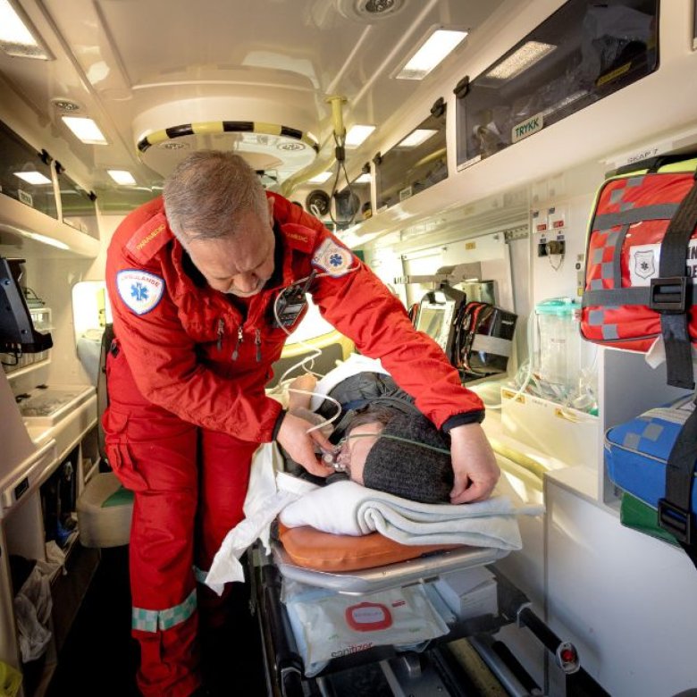 Ambulansearbeider gir medisinsk hjelp til pasient inne i en ambulanse.
