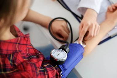 En helsearbeider måler blodtrykket på en person med en blodtrykksmansjett.